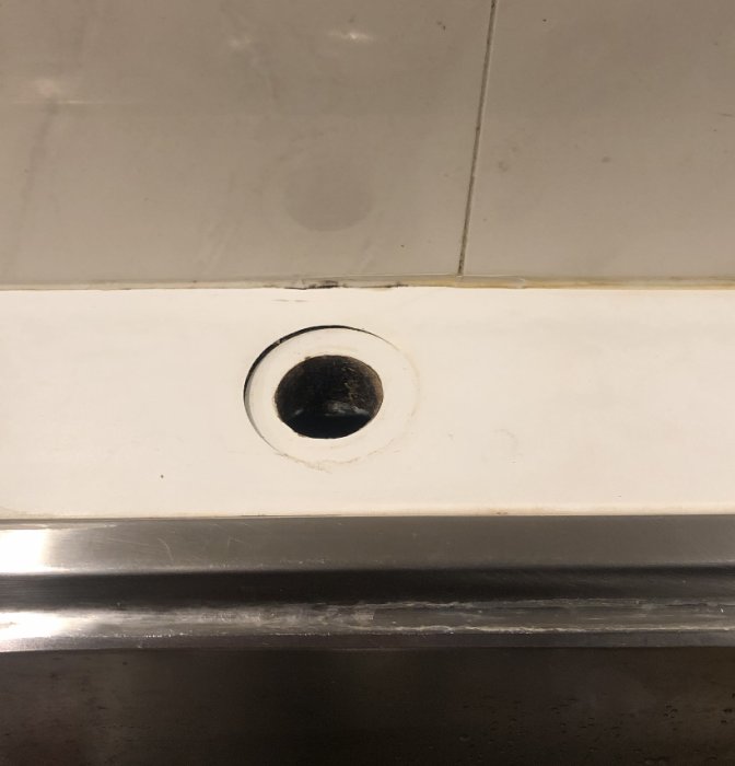 Skadad bänkskiva med en sänkning runt en mörk öppning där blandaren suttit.