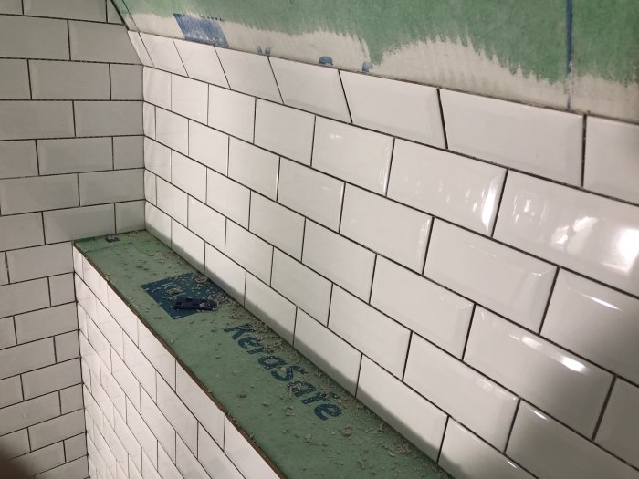 Vitt kakel som är delvis installerat på en vägg med en synlig hörna och övergång.