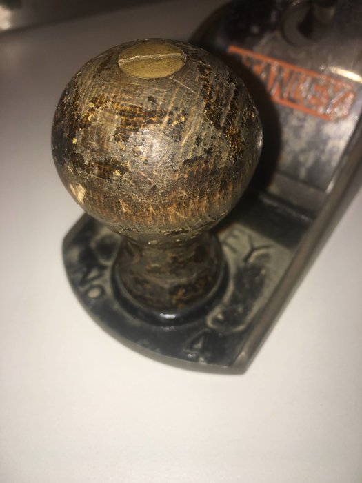 Närbild av en sliten träknopp på en gammal Stanley No 4 hyvel med synlig märkning.
