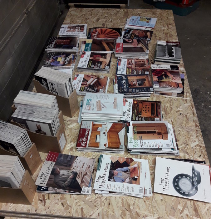 Stapel med utgåvor av tidskriften Fine Woodworking från 1975-2014 utspridda på ett träbord.