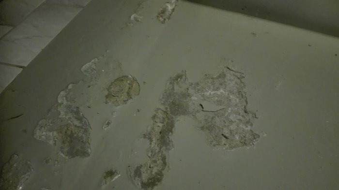 Flagnat och skadat betonggolv i ett källarutrymme med synliga rester av grå färg.