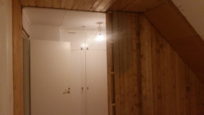 Delvis omålat rum med synlig vägg av trä och vit garderob indikerar plats av tidigare vägg.