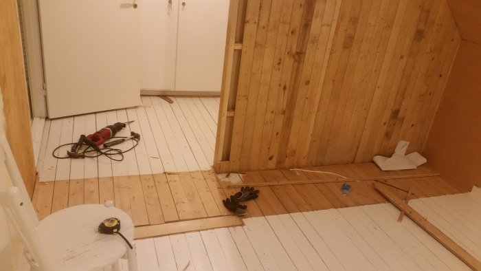 Delvis riven trävägg i renoveringsprojekt med synliga verktyg och omålade ytor.