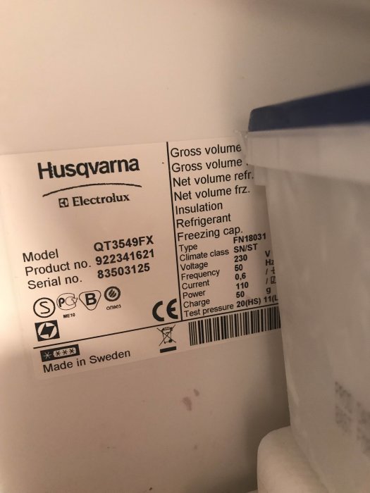 Etikett på en Husqvarna-Electrolux frys med modellnummer och specifikationer, nära ett isfack.