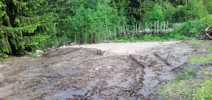 En nyanlagd grusplatta omgiven av skog med dräneringsrör synligt och spår efter grävmaskin.