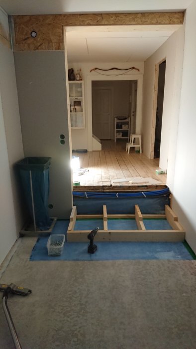 Påbörjade trappsteg i ett hus under renovering med verktyg och skyddsplast på golvet.