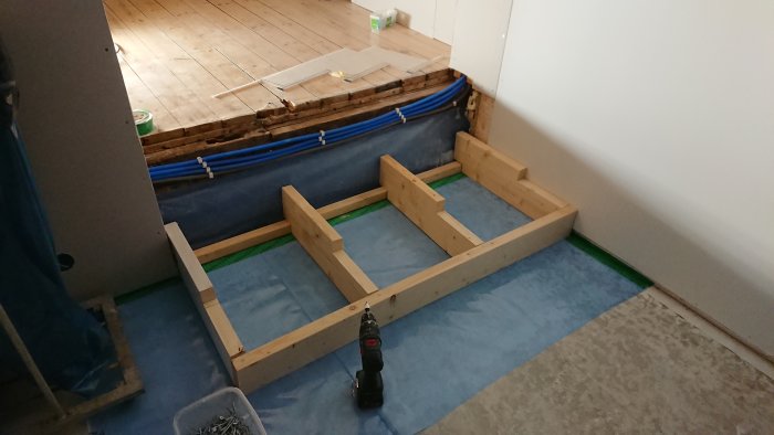 Grundkonstruktion av en trätrappa i ett rum under renovering med verktyg och byggmaterial.