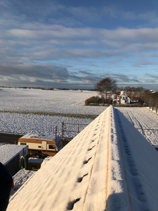 Vy över ett snötäckt byggeområde med hus, byggmaterial och maskiner från ett tak.