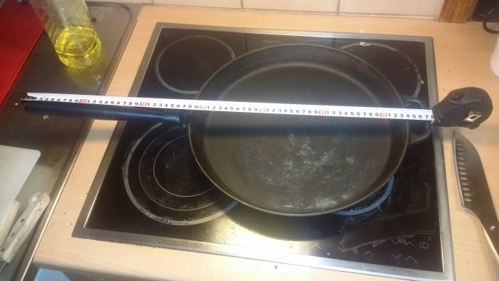 Stor stekpanna på spis bredvid ett måttband och en flaska matolja.