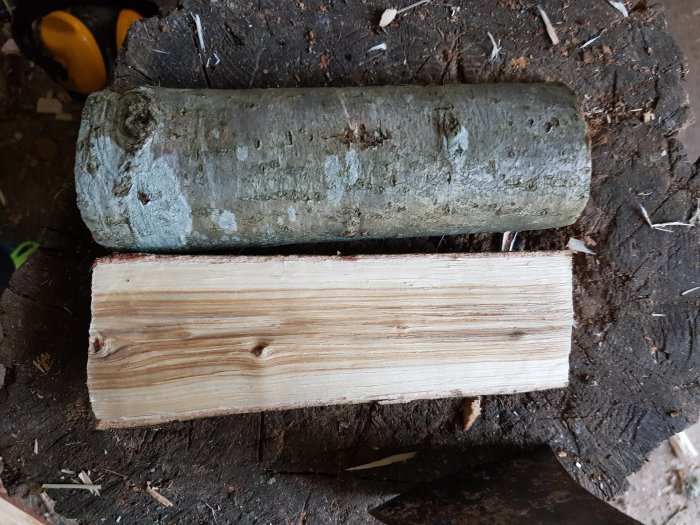 En hög med slipat trä och en stock på en stubbe i en verkstad.