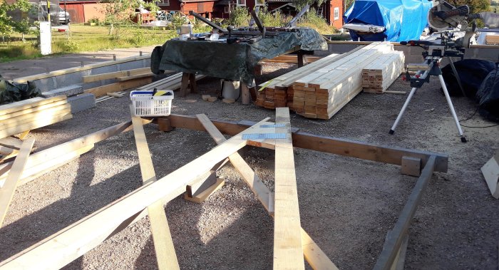 Byggplats med trämaterial och verktyg för konstruktion av takstolar under sommarlovet.