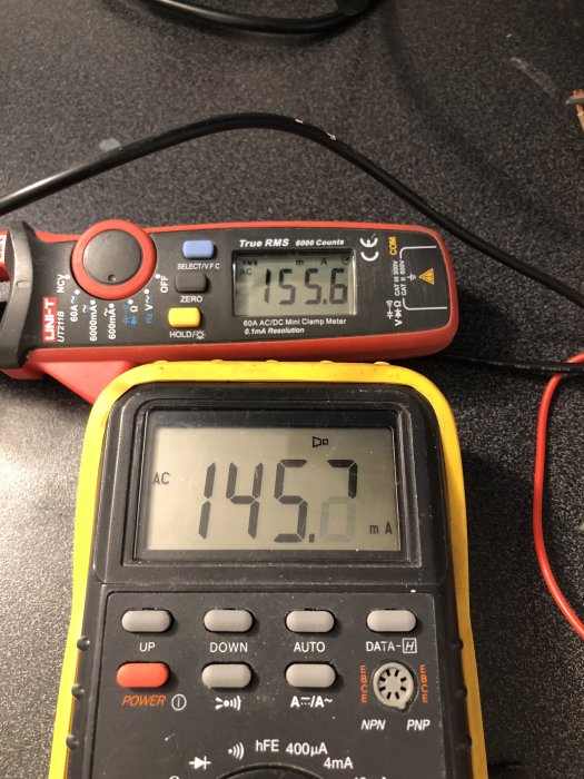Multimeter och strömtång mäter strömförbrukning 155.6 mA på en inkopplad USB-adapter.