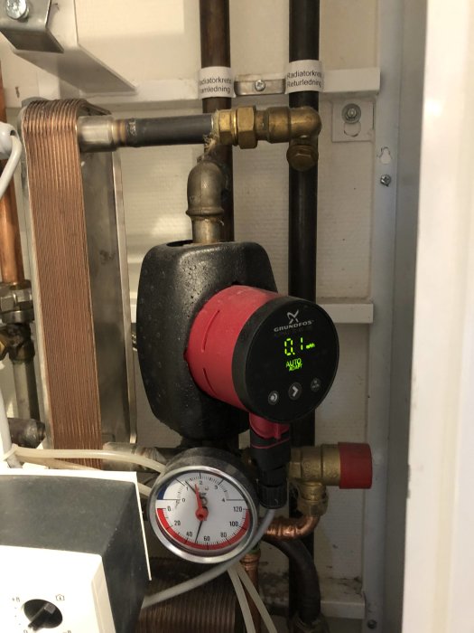 Centralvärmeinstallation med cirkulationspump, mätare och rörledningar.