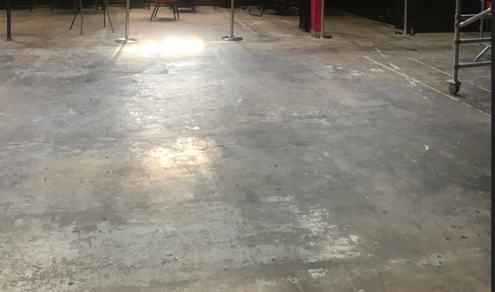 Slitet betonggolv i en tom festvåning redo för renovering eller målning.