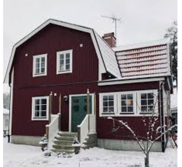Rött hus i snö med otydlig husknut till höger om entrédörren.