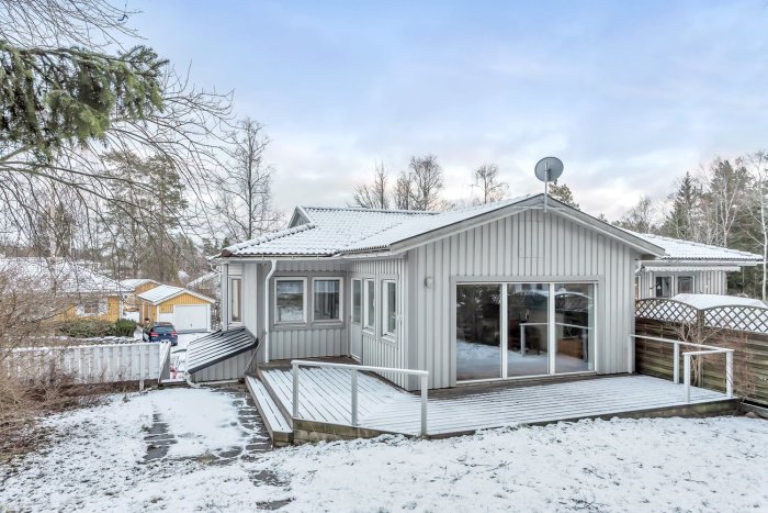 Parhus i suterräng med snötäckt tomt och sluttande skog i bakgrunden.