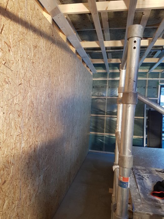 Innervägg med OSB-skivor och bjälklag i ett byggprojekt, synlig ventilation och isolering.