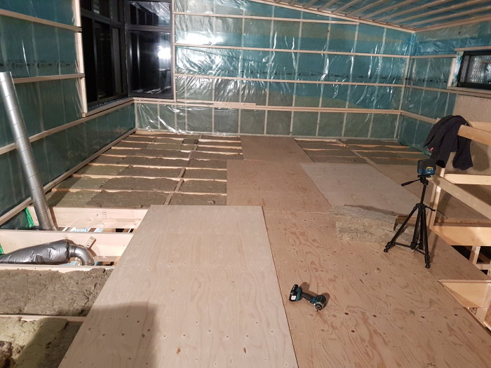 Renoveringsprojekt med OSB-golv, isolering, ångspärr och ventilation under installation på ett byggställe.