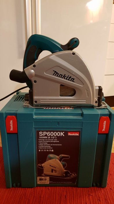 Makita handhållen cirkelsåg på dess blå förvaringslåda, modell SP6000K.