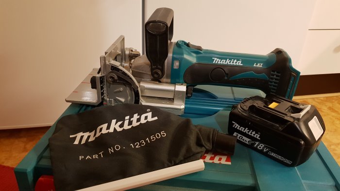 Makita fräs med batteri och väska på arbetsbänk.