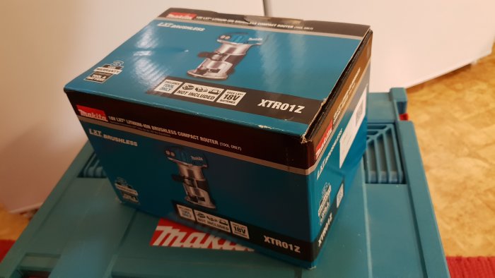 Makita 18V LXT borstlös kompakt fräs i låda på blå arbetsbänk.