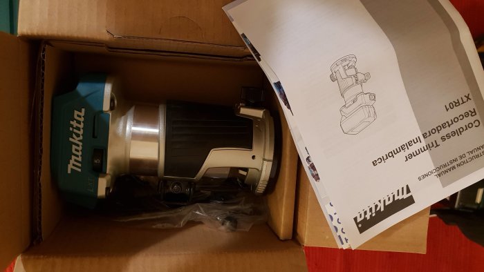 Makita fräs i en öppen kartong bredvid instruktionshäfte.