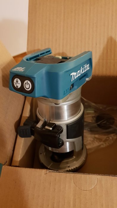 Blå Makita-fräs med BL-motor och batteriindikator placerad i en kartong.