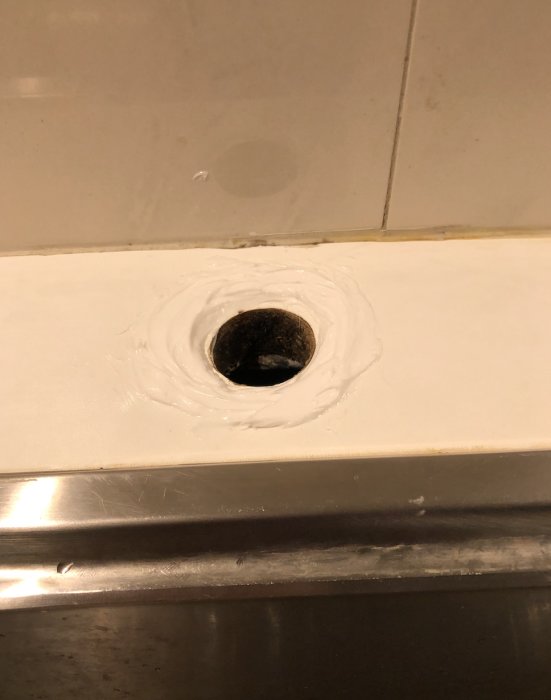 Silikonapplicering runt nedsänkning och täckbricka i badrummet.
