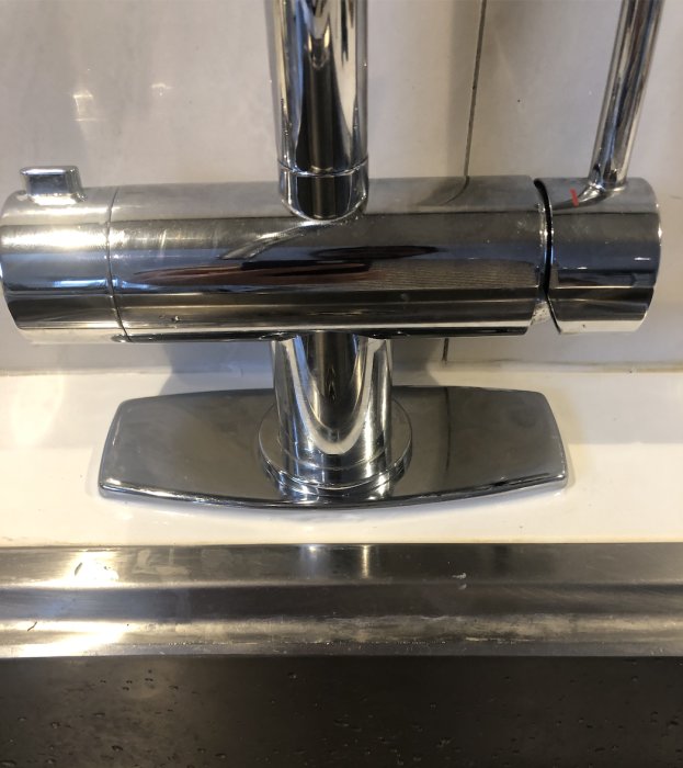 Kromad kökskran monterad på diskbänk med silikon i nedsänkningen och runt täckbrickan.