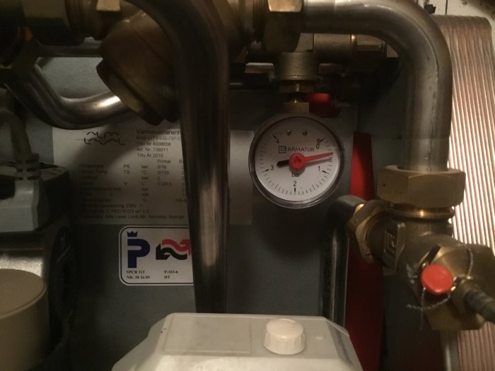 Manometer på värmeväxlare visar tryck nära 1 bar, fråga om rätt tryck med röd pil.