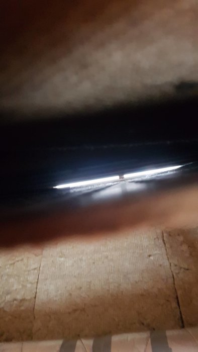 Inblick i en mörk, isolerad takkonstruktion med synbart ljusinsläpp som visar en kring 2 cm bred luftspalt.