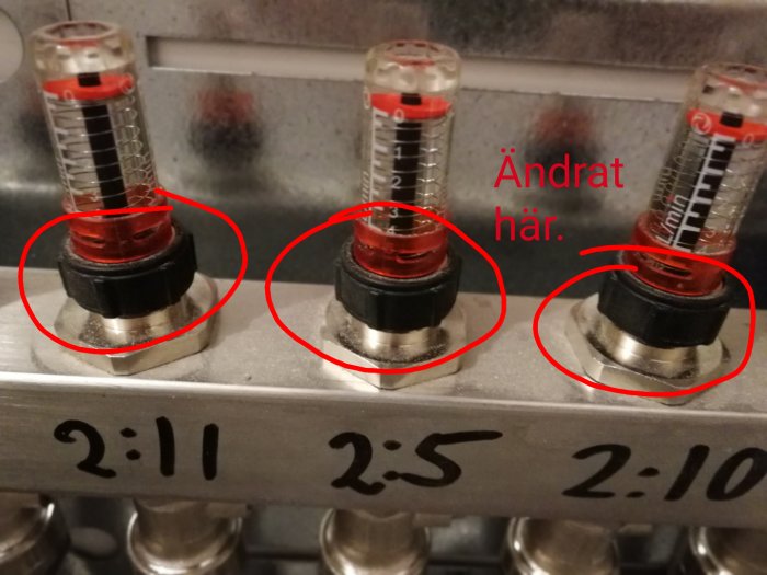 Flödesregulatorer på värmesystem med justerade röda ventiler och antecknad text.