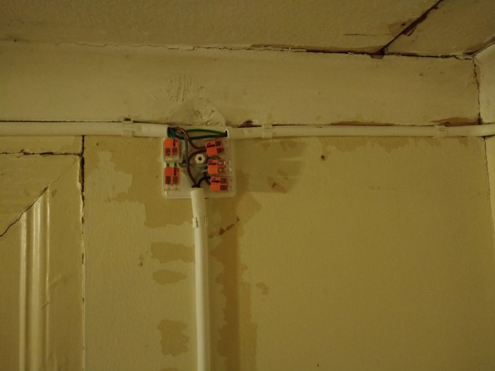 Kablar och dosa installerade på en vägg med spacklade ytor redo för målning.