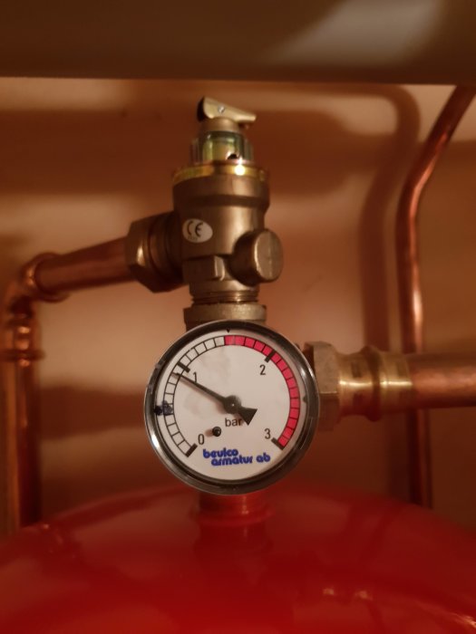 Manometer visar tryck i värmesystem, nål strax under 2 bar, kopplad till röd expansionskärl.