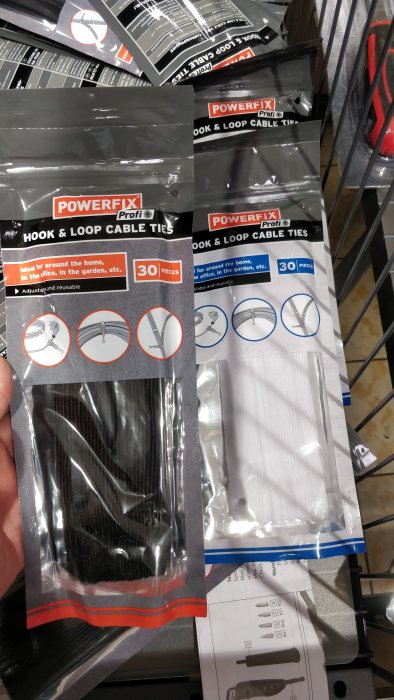 Förpackade svarta och vita kardborreband kabelbindare märkta "POWERFIX" på hyllan.