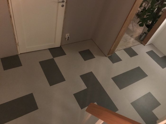 Marmoleum Click golv i hall med mönster av gråa rektanglar, ofärdiga väggar och en dörröppning.