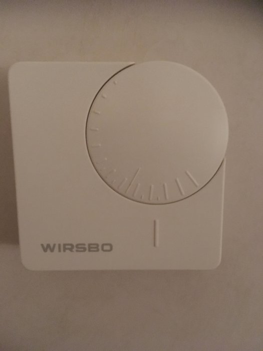 Vit termostat med vred och märkning "WIRSBO" på en vägg.