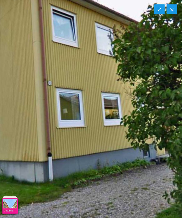 Hus med gul plåtfasad och fönster utan synliga träfoder.