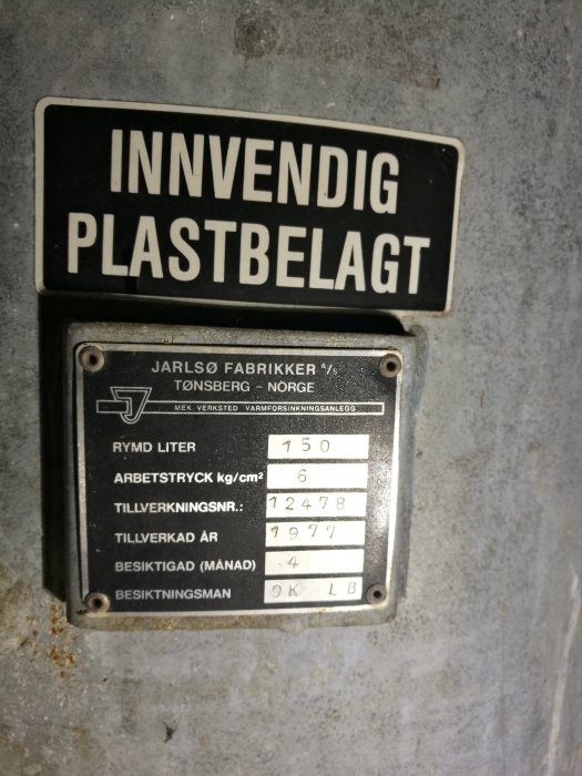 Skyltar på en hydrofor med texten "INNVENDIG PLASTBELAGT" och tekniska specifikationer från 1977.