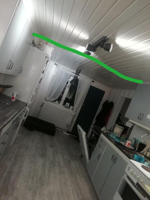 Kök med vit inredning och grönt markerat område där gammal vägg gick, intressepunkt för renovering.