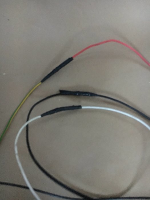 Gamla elledningar med skarvtejp ligger på en yta, indikerande en amatörmässig installation.