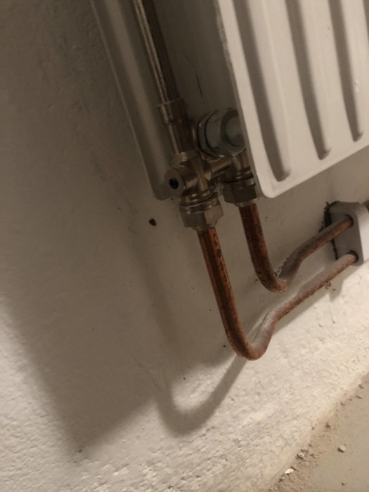 Element med anslutna kopparrör i ett 2-rörs uppkopplingssystem mot en vit vägg.
