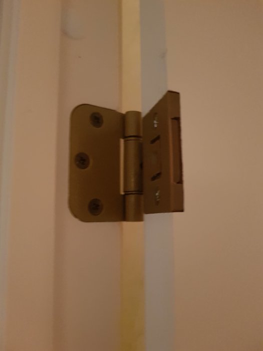 Dörrgångjärn monterat på karmen med synlig glipa där dörren tar emot.