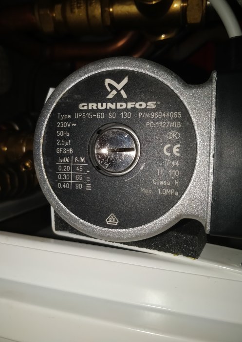 Närbild på en Grundfos cirkulationspump med hastighetsinställningar synliga på en justerbar switch.