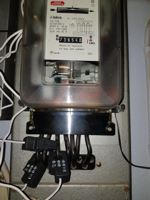 En elmätare med klämmor för trådlös energimätning fästa på tre inkommande kablar.