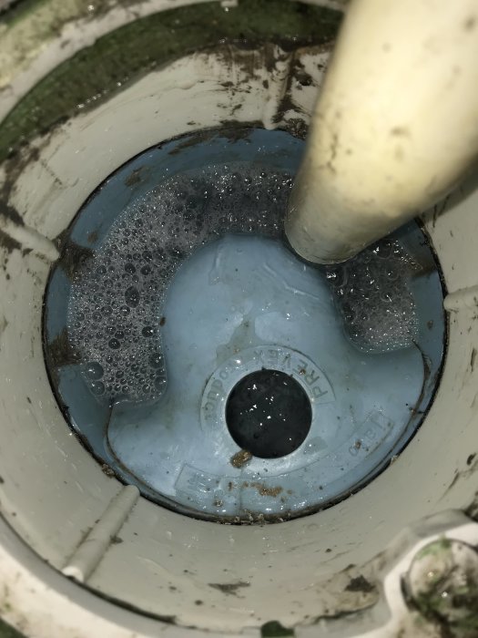 Närbild på en öppen Prevex golvbrunn utan täcklock, synlig skrift och vatten i brunnen.