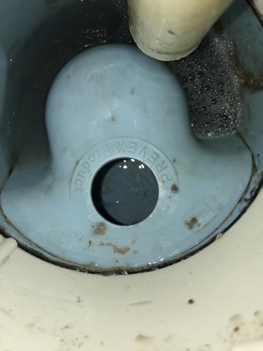 Prevex golvbrunn i behov av ett täcklock för rensning, vatten och smuts synlig.