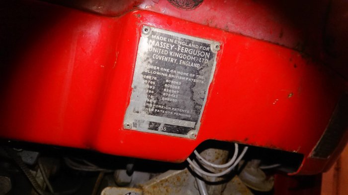 Bild på ett identifikationsmärke på en röd Massey Ferguson traktor med serienummer och information om brittiska och utländska patent.