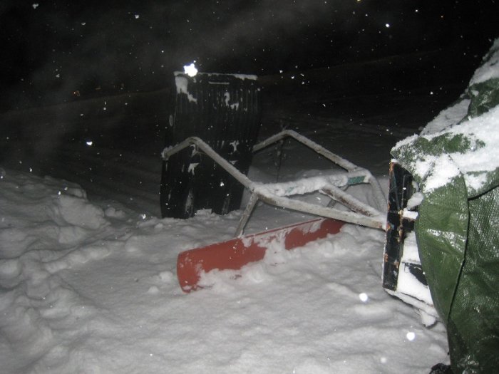 Handgjord spårmaskin av rör och avloppsrör i snön under kvällshimmel.