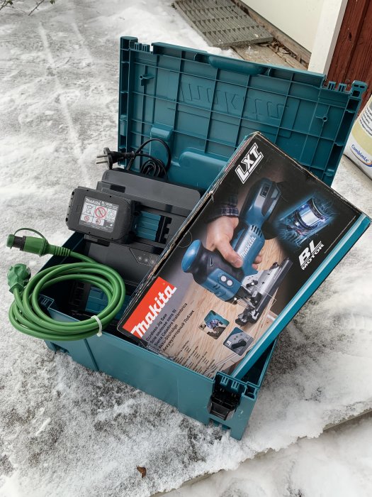 Nytt Makita borrmaskin kit med låda och motorvärmare på ett snöigt underlag.